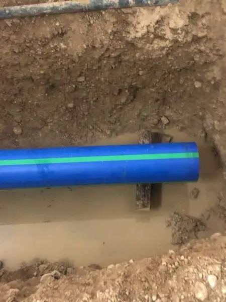 New blue water service pipe bedded in an open trench before backfill