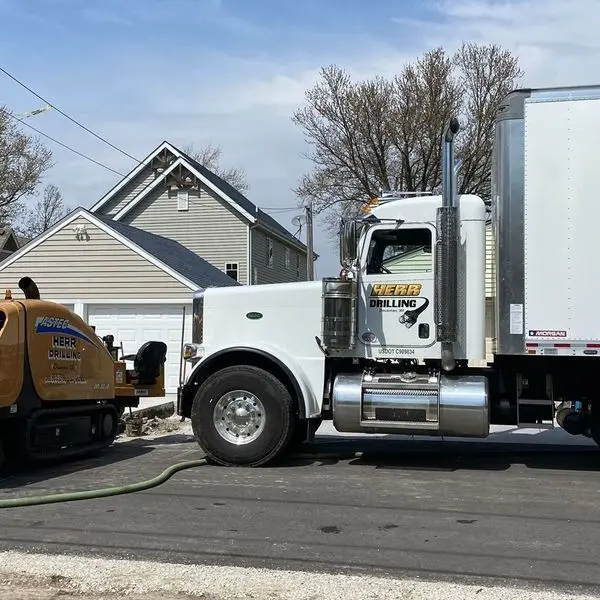 Herr Drilling semi truck and tracked directional drill set up on a residential street for a trenchless bore