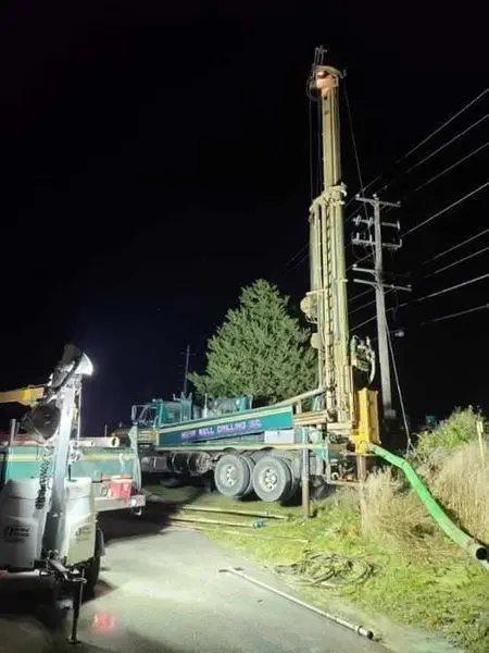 Herr Well Drilling rig working after dark beside a power pole on a tight urban well job in West Allis, WI