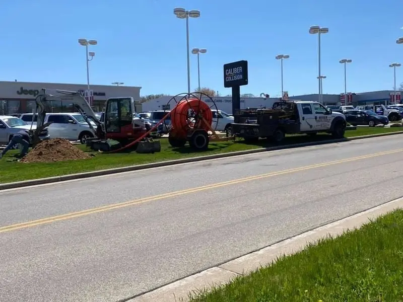 Herr Well Drilling excavator and equipment trailer staged on a commercial site for well pump installation in Milwaukee, WI